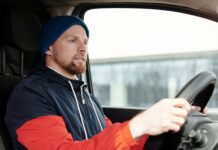 Brodaty mężczyzna w czapce prowadzi auto zimą, skupiony na drodze
