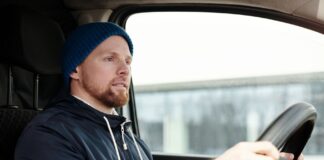Brodaty mężczyzna w czapce prowadzi auto zimą, skupiony na drodze