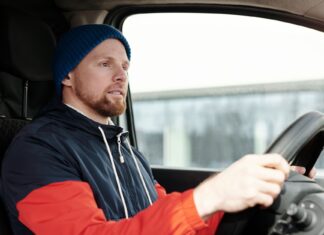 Jak przygotować samochód do zimy: kompleksowy poradnik dla kierowców Brodaty mężczyzna w czapce prowadzi auto zimą, skupiony na drodze