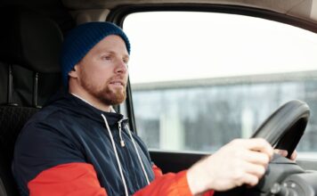 Jak przygotować samochód do zimy: kompleksowy poradnik dla kierowców Brodaty mężczyzna w czapce prowadzi auto zimą, skupiony na drodze