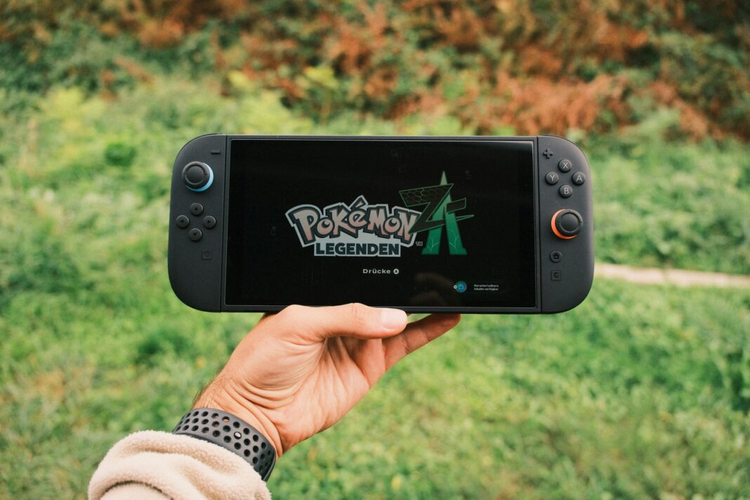 Gracz trzyma przenośną konsolę z włączoną grą Pokémon Legends na dworze