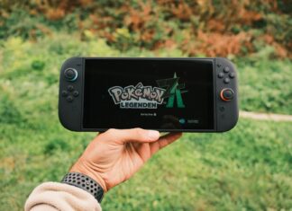 Gracz trzyma przenośną konsolę z włączoną grą Pokémon Legends na dworze