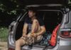 Jak przygotować auto do długiej trasy: kompleksowy poradnik przeglądu, wyposażenia i bezpieczeństwa Mężczyzna w bagażniku SUV-a wiąże buty przed długą podróżą