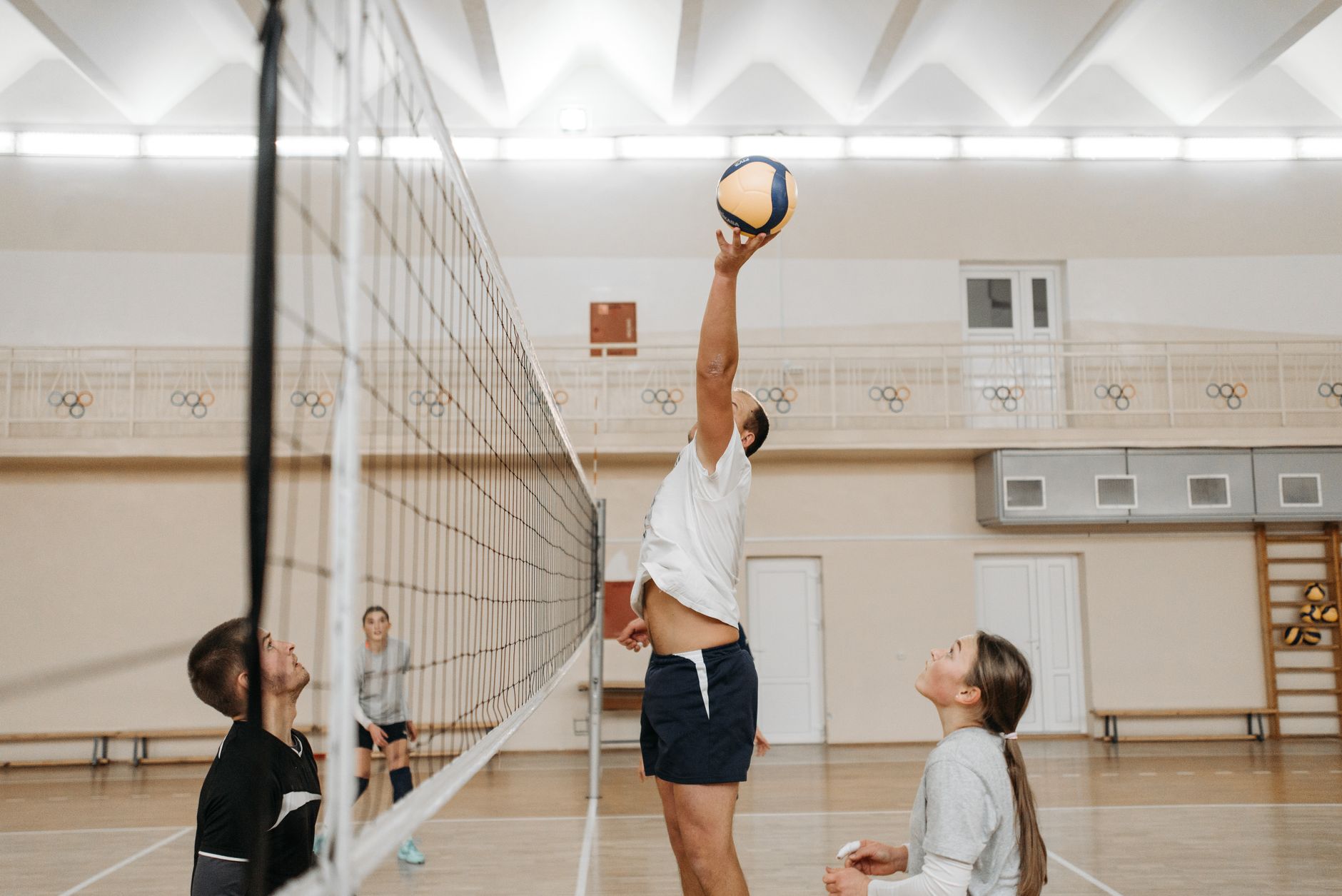Trzech siatkarzy w akcji podczas meczu w hali sportowej