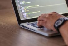 Ciągła integracja dla projektów open source: workflow DevOps, code review i automatyczne testy Programista piszący kod DevOps na laptopie z widocznym ekranem