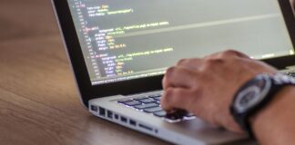 Programista piszący kod DevOps na laptopie z widocznym ekranem