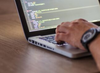 Programista piszący kod DevOps na laptopie z widocznym ekranem