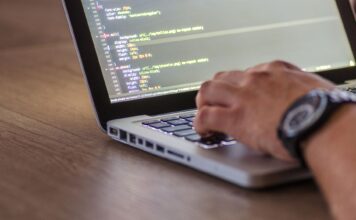 Ciągła integracja dla projektów open source: workflow DevOps, code review i automatyczne testy Programista piszący kod DevOps na laptopie z widocznym ekranem